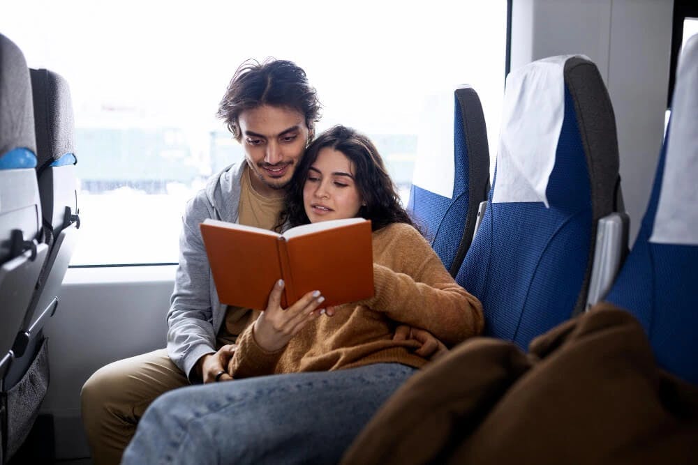 Młodzi ludzie podróżujący pociągiem czytają książkę